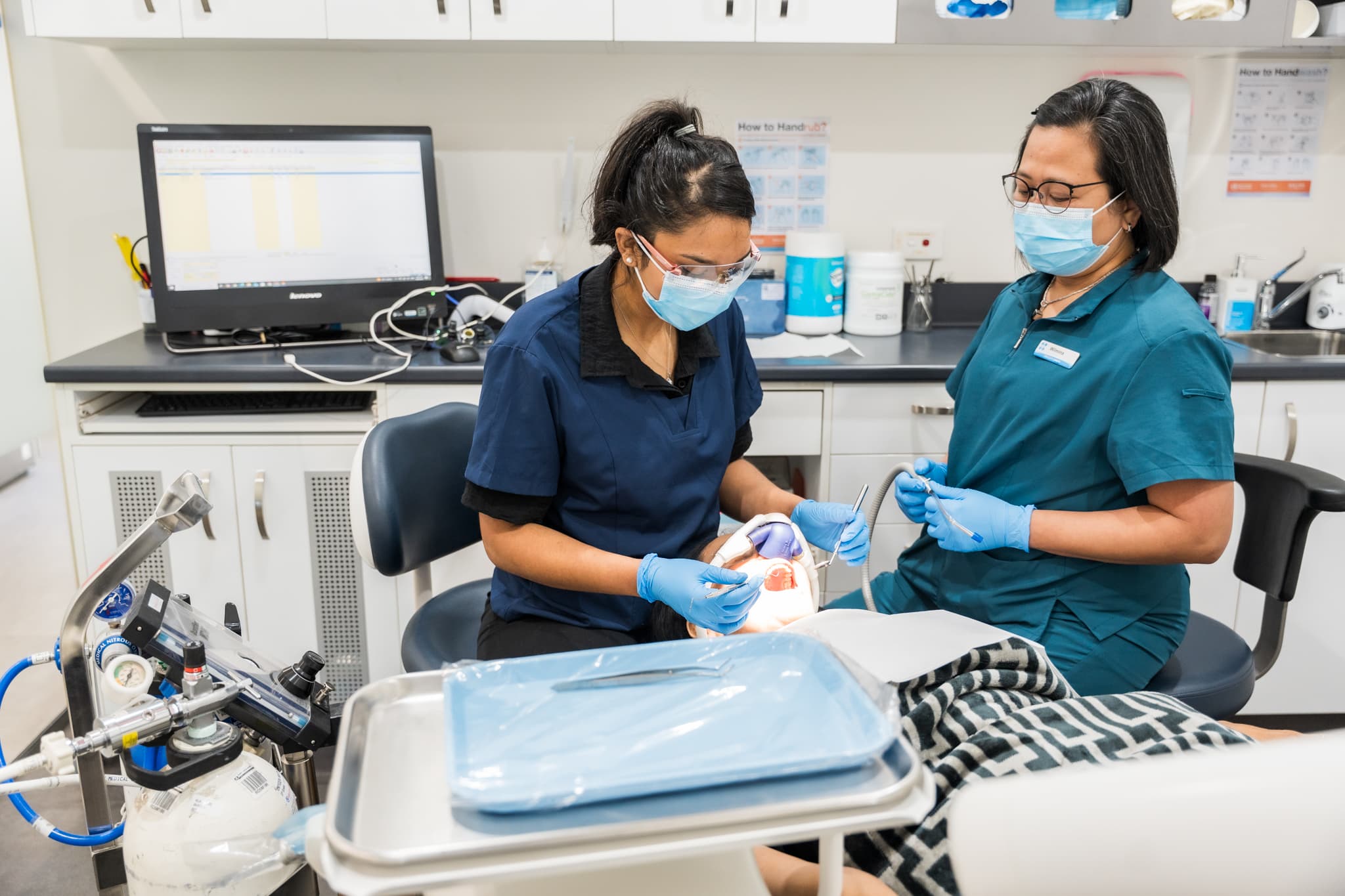 Dental team performing a check-up with protective masks and equipment.