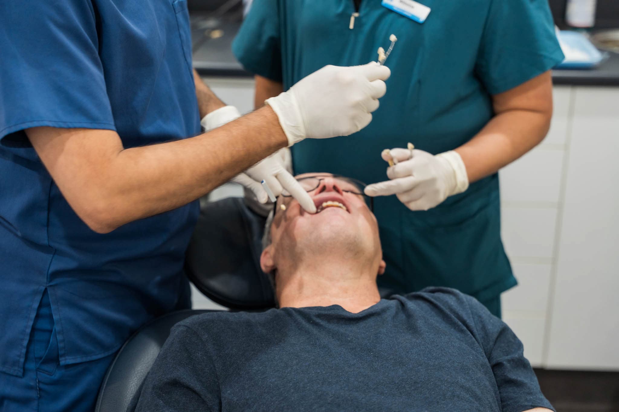 Dentist performing treatment on male patient during dental procedure