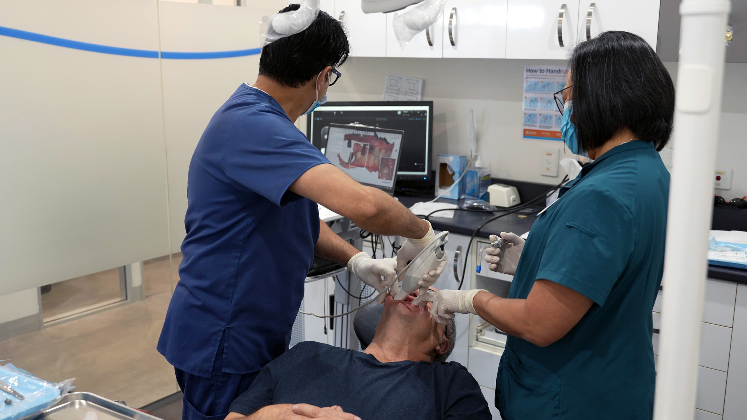 Dentist performing digital scan with assistant during TMJ assessment